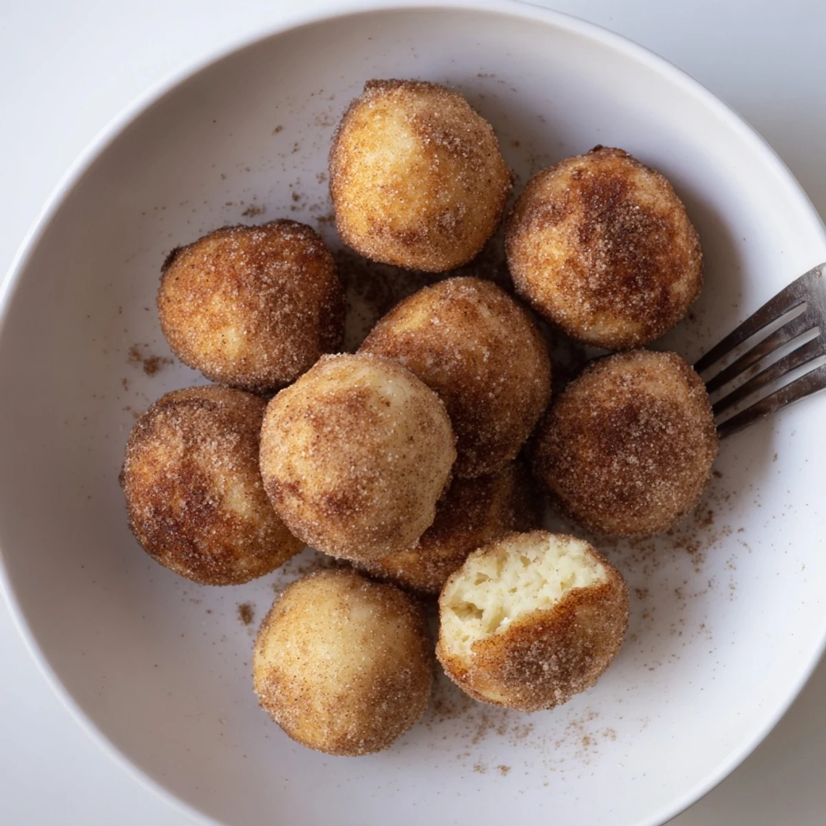Knusprig frittierte Quark-Donutbällchen, warm serviert und mit Zimt-Zucker bestäubt.  