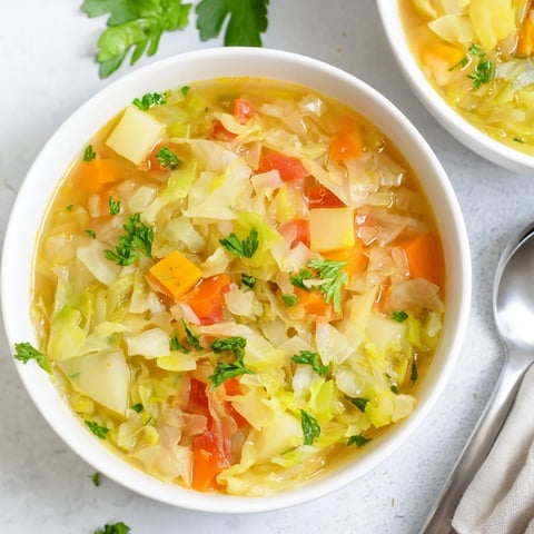 Einfache und herzhafte Kohl-Suppe mit frischen Kräutern und buntem Gemüse serviert.